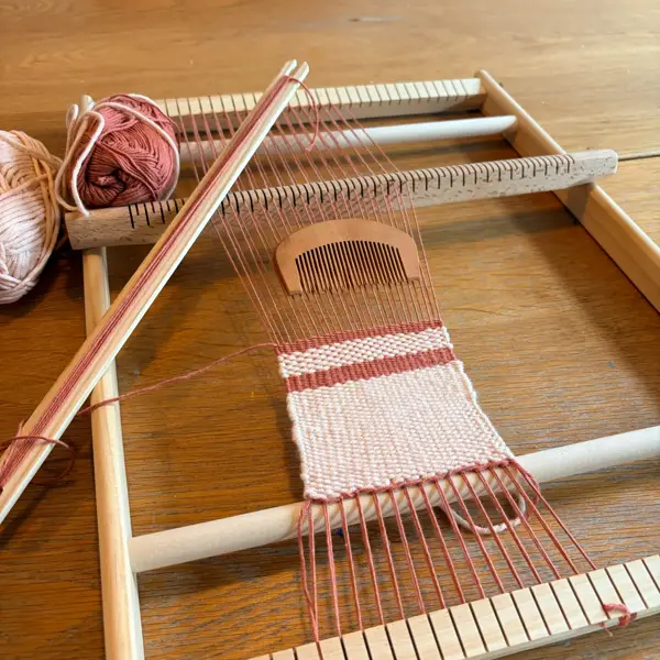 Verified buyer photo: LoomCraft Medium weaving loom mid-project, rose and terracotta yarn